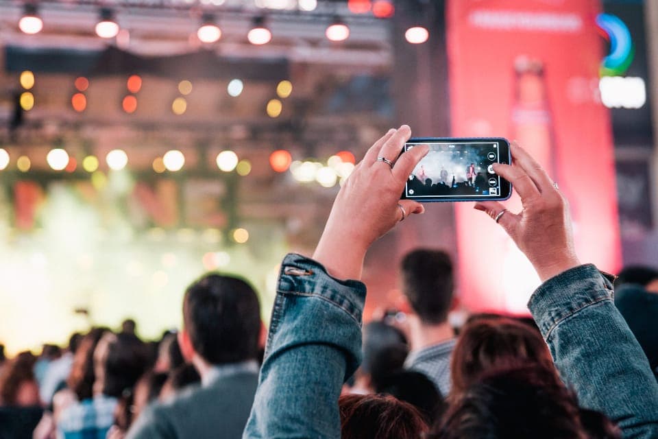 Person filming a live performance on a smartphone